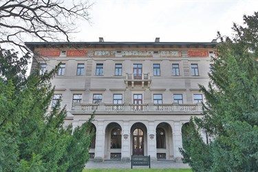 Budova se zdobenou fasádou a stromy v popředí