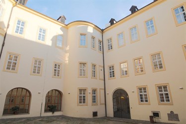 Nádvoří budovy s bílou fasádou a obloukovými okny