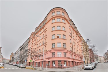 Rohová budova s růžovou fasádou v ulici