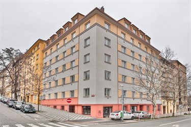 Rohová obytná budova s růžovou fasádou